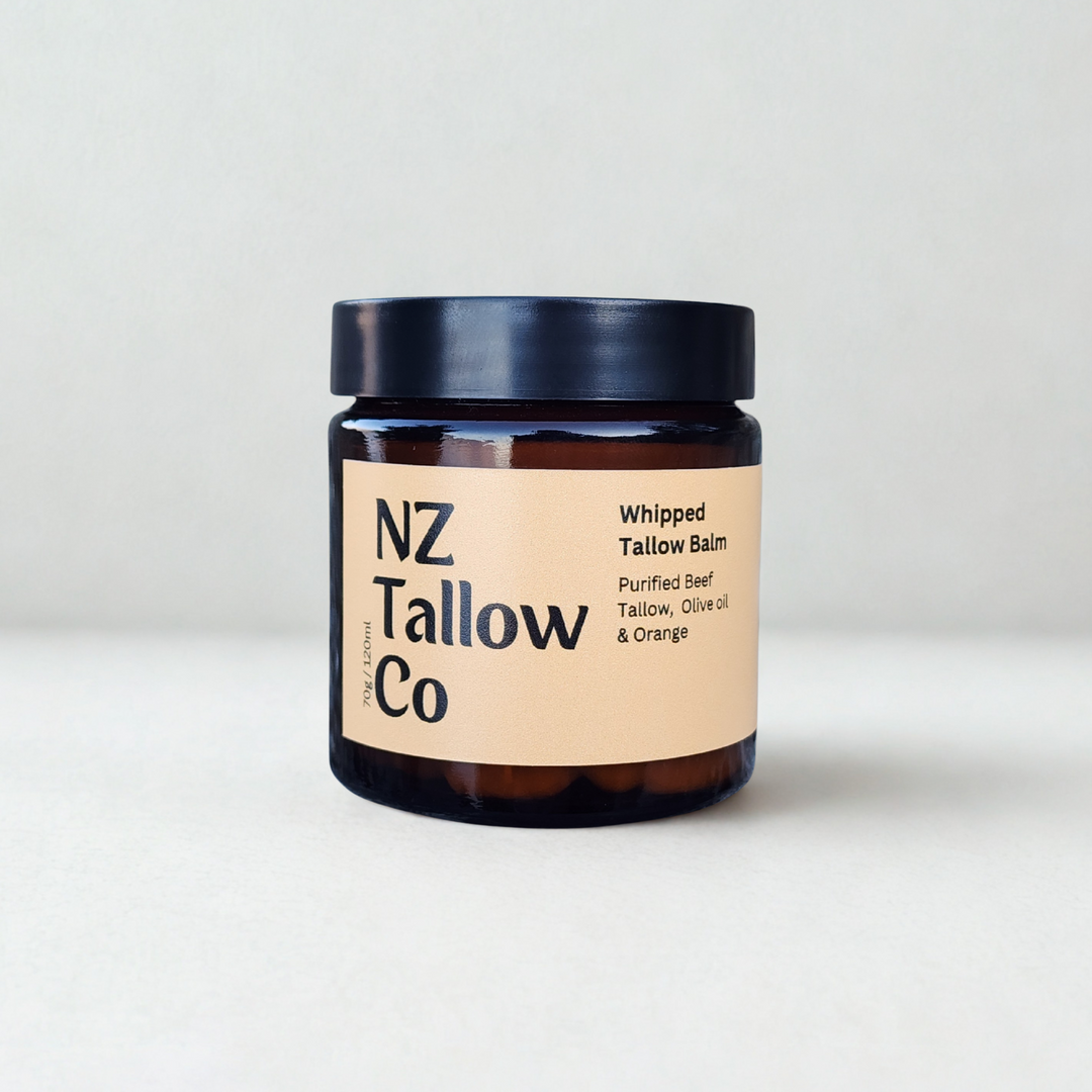 Jar of NZ Tallow Co whipped tallow balm on a light background and oranges next to it